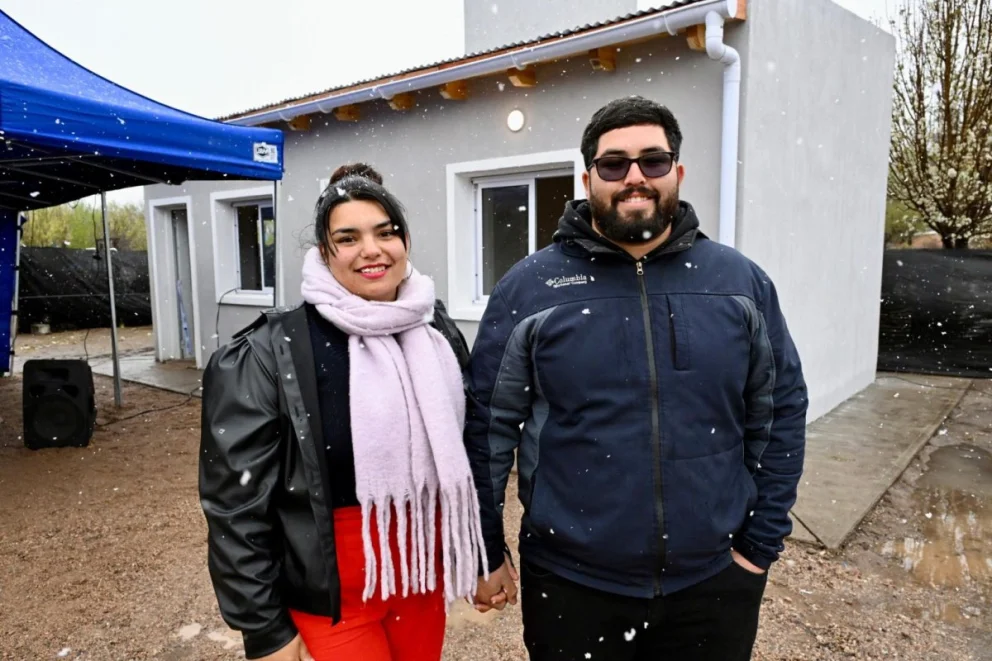 Una pareja posa en medio de la nieve. Atrás, la casa en la que comenzarán a vivir